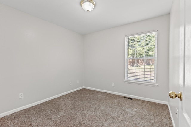 spare room featuring carpet floors, visible vents, and baseboards