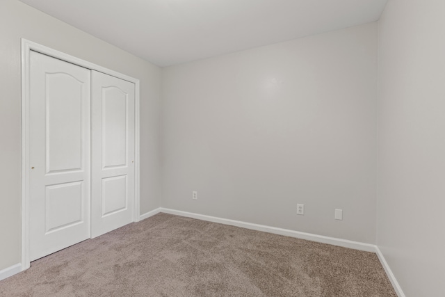 unfurnished bedroom with a closet, baseboards, and carpet flooring