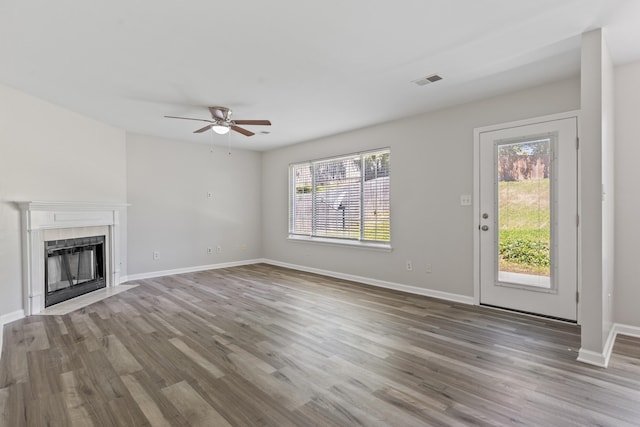 unfurnished living room featuring a tile fireplace, a healthy amount of sunlight, and wood finished floors