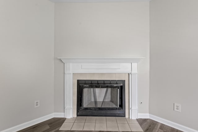 room details with a tiled fireplace, wood finished floors, and baseboards