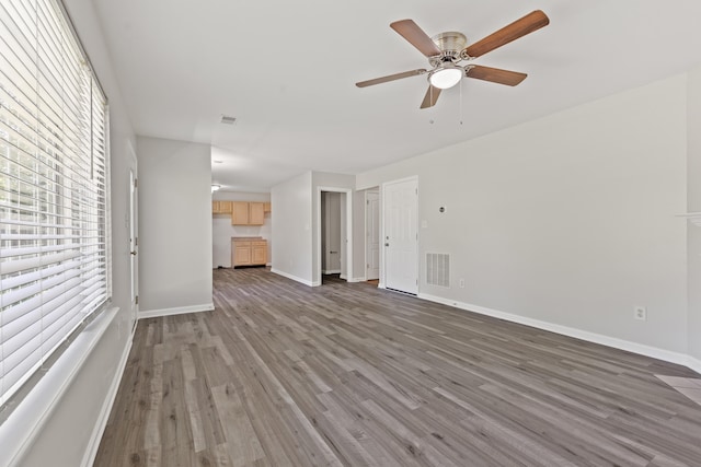 unfurnished living room featuring visible vents, ceiling fan, baseboards, and wood finished floors