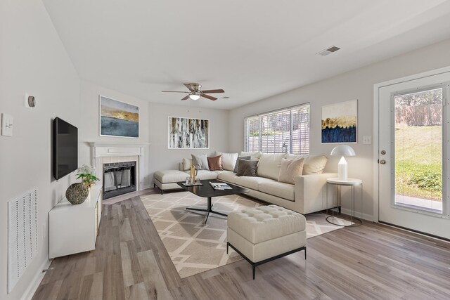 living room with a tile fireplace, visible vents, and light wood-style floors