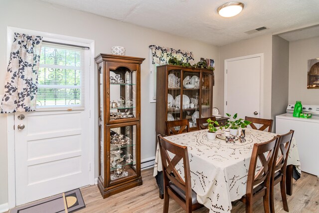 dining room featuring a textured ceiling, washer / clothes dryer, and light hardwood / wood-style flooring