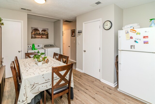 dining room featuring light wood-type flooring, a textured ceiling, and separate washer and dryer