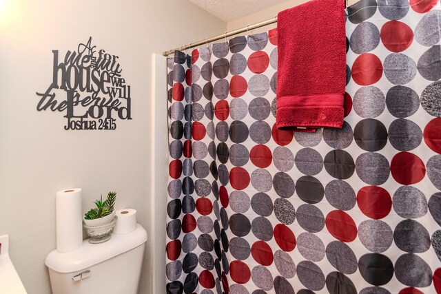 bathroom with a shower with shower curtain and toilet