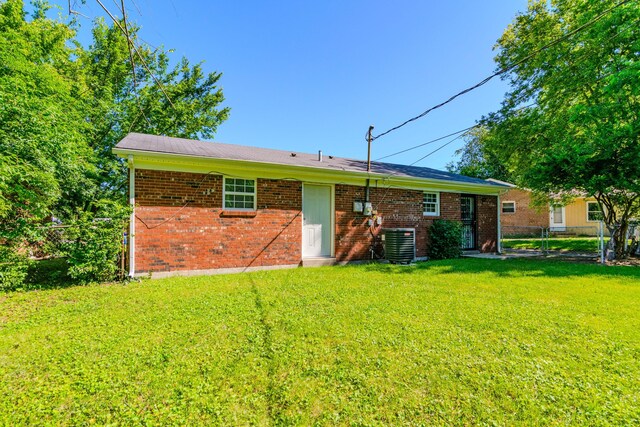 back of property featuring central AC and a lawn