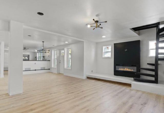 unfurnished living room with light wood-type flooring and a chandelier