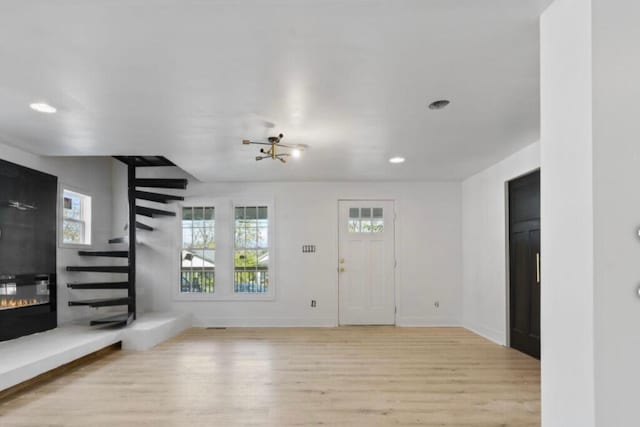 unfurnished living room featuring light wood-type flooring and an inviting chandelier