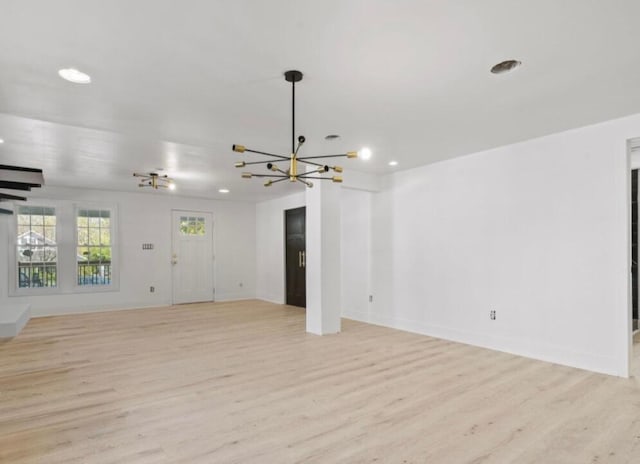 unfurnished living room with light wood-type flooring and a chandelier