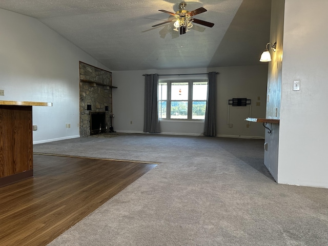 unfurnished living room with baseboards, dark wood-style floors, ceiling fan, a stone fireplace, and high vaulted ceiling