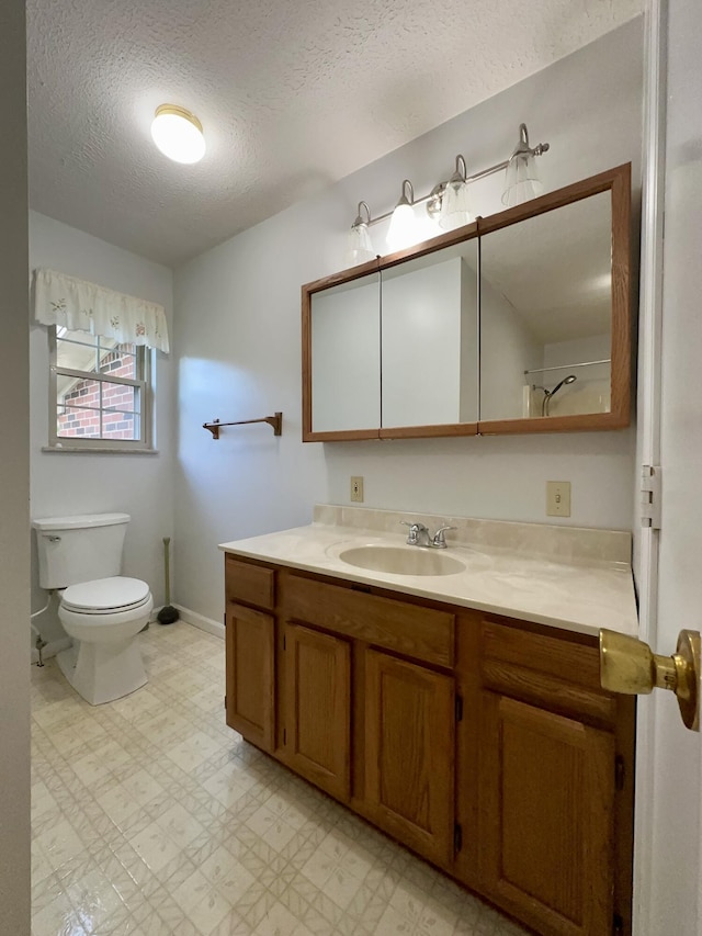 bathroom featuring toilet, vanity, a textured ceiling, and tile patterned floors