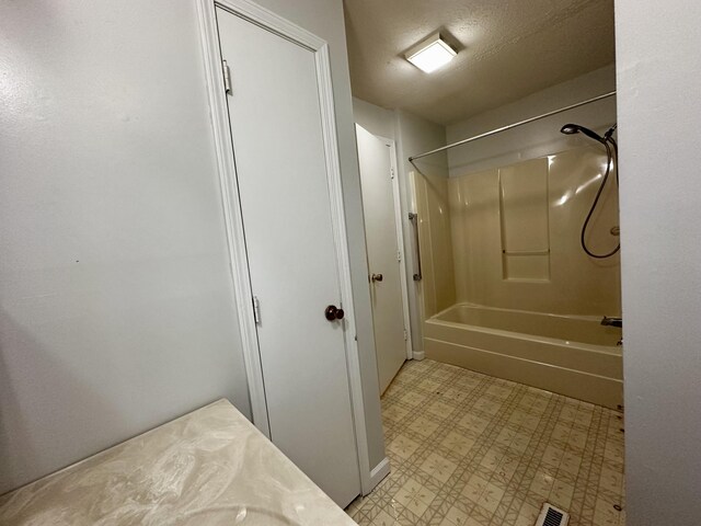 bathroom featuring  shower combination and a textured ceiling