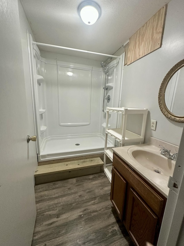 full bath with a textured ceiling, a stall shower, wood finished floors, and vanity