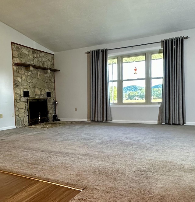 unfurnished living room with lofted ceiling, carpet flooring, and a stone fireplace