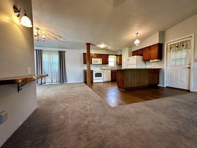 kitchen featuring dark carpet, kitchen peninsula, white appliances, and decorative light fixtures