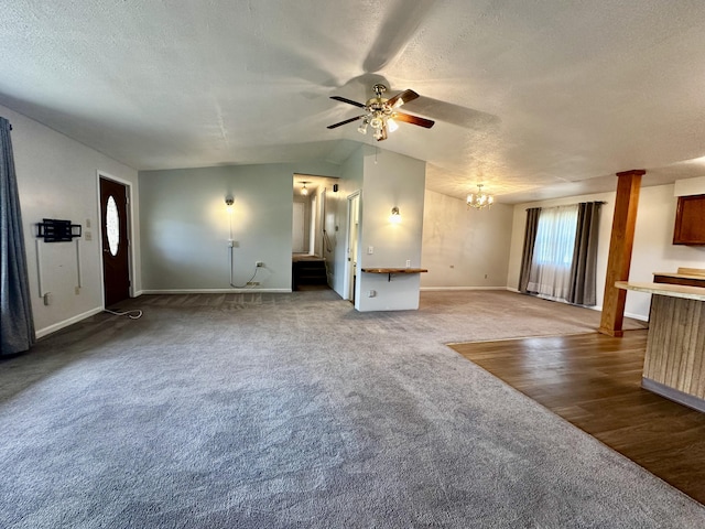 unfurnished living room with ceiling fan with notable chandelier, plenty of natural light, carpet floors, and a textured ceiling