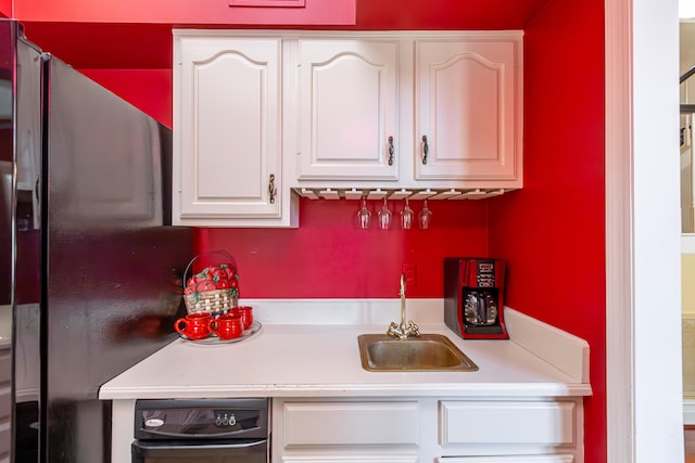 kitchen featuring white cabinets, black fridge, and sink