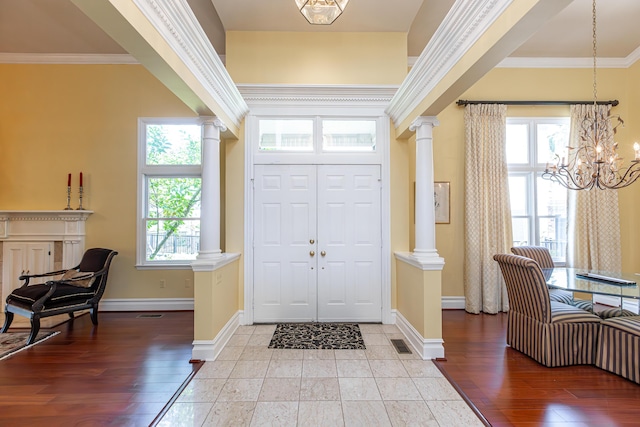 entryway featuring a wealth of natural light, ornamental molding, and decorative columns