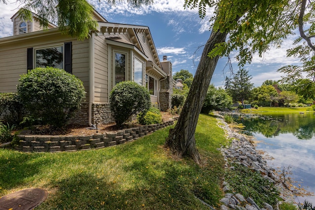 view of side of property with a yard and a water view