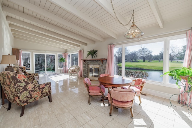 sunroom / solarium featuring lofted ceiling with beams, a water view, a healthy amount of sunlight, and a brick fireplace