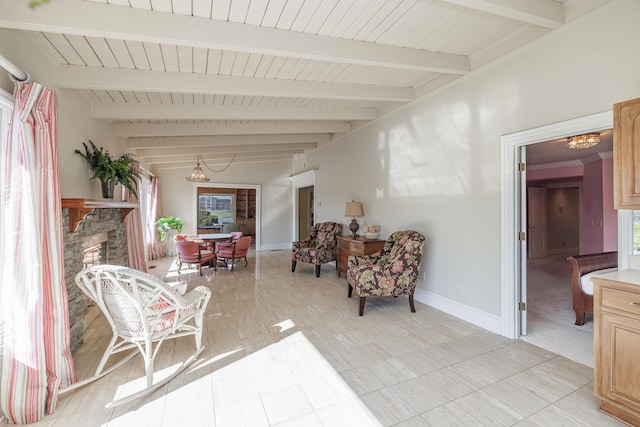 sitting room featuring a healthy amount of sunlight, a fireplace, lofted ceiling with beams, and a notable chandelier