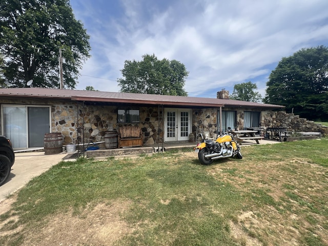 back of property featuring french doors and a lawn