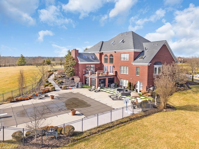 back of property featuring brick siding, fence, a lawn, and a patio area