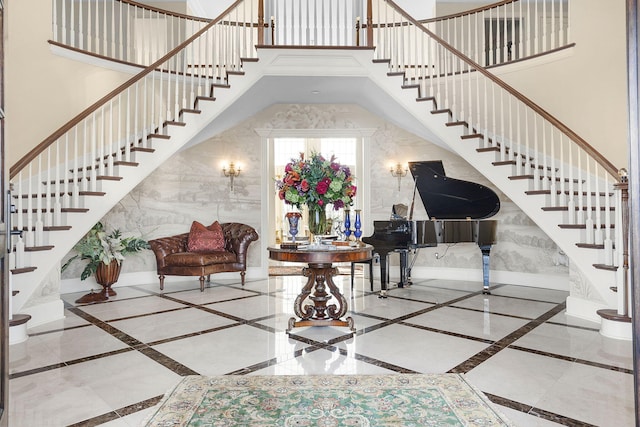 foyer featuring baseboards, a towering ceiling, and stairs