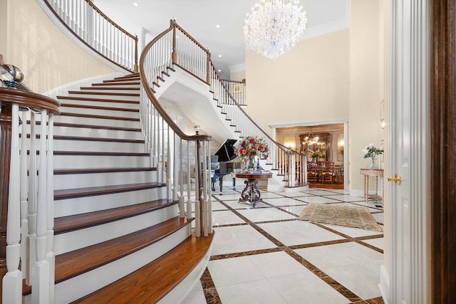 foyer with ornamental molding, stairway, an inviting chandelier, baseboards, and a towering ceiling