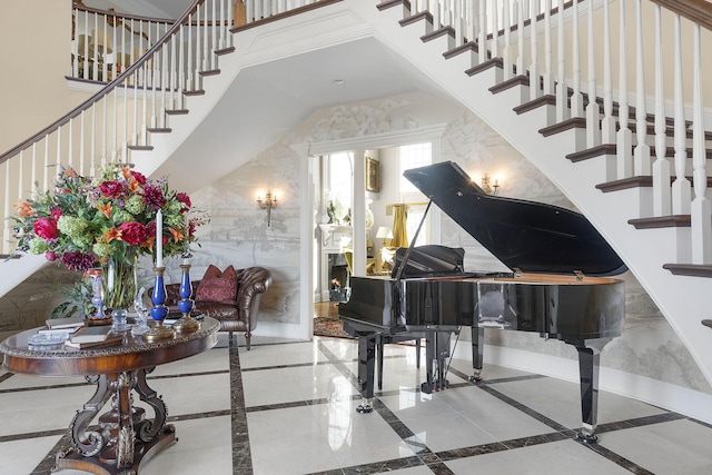 living area with stairway, baseboards, and a towering ceiling