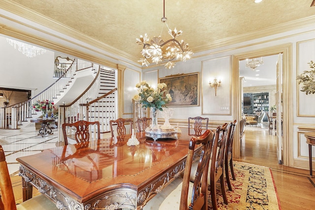 dining space with light wood finished floors, crown molding, stairs, and an inviting chandelier