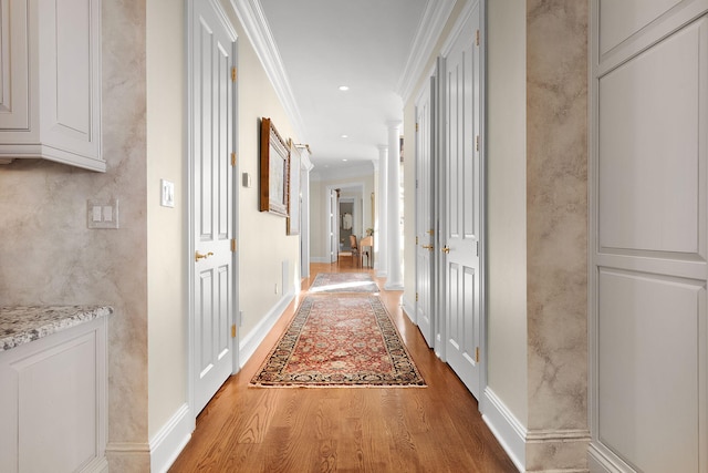 corridor featuring wood finished floors, baseboards, decorative columns, recessed lighting, and ornamental molding