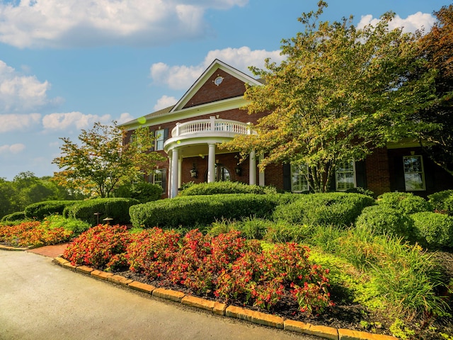 view of front of house featuring a balcony and brick siding