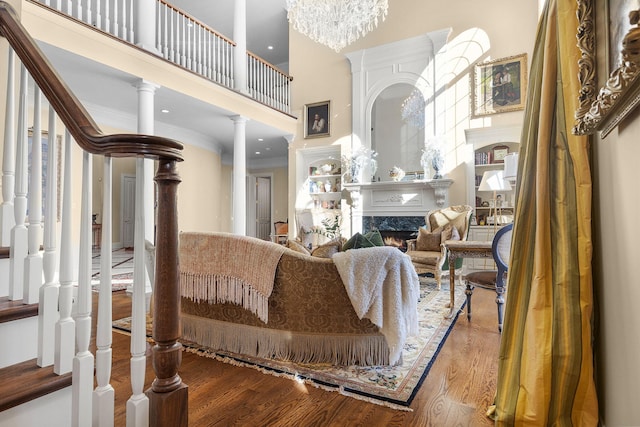 living area with stairway, wood finished floors, a premium fireplace, ornamental molding, and a towering ceiling