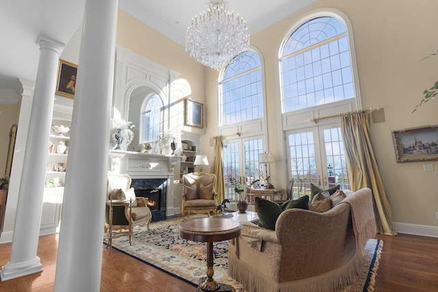 living room featuring wood finished floors, baseboards, decorative columns, a high end fireplace, and crown molding