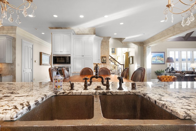 kitchen with light stone countertops, recessed lighting, ornamental molding, a sink, and black microwave