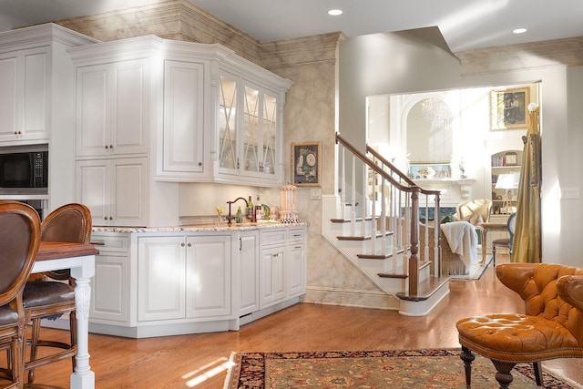 bar with recessed lighting, built in microwave, light wood-style flooring, and stairway