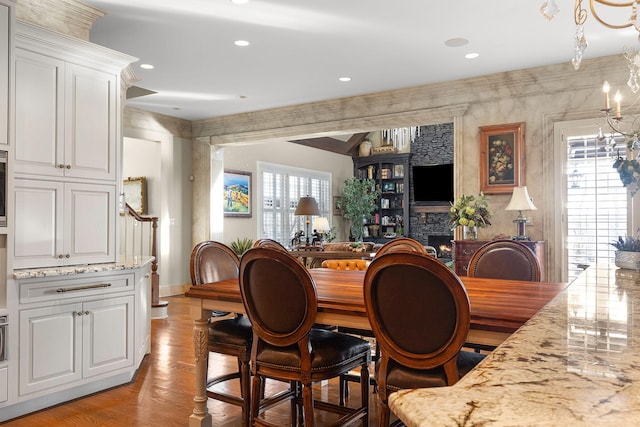 dining room featuring recessed lighting, light wood-type flooring, baseboards, and a stone fireplace