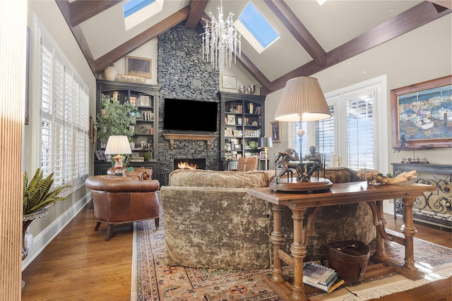 living room featuring a fireplace, beam ceiling, a skylight, and wood finished floors