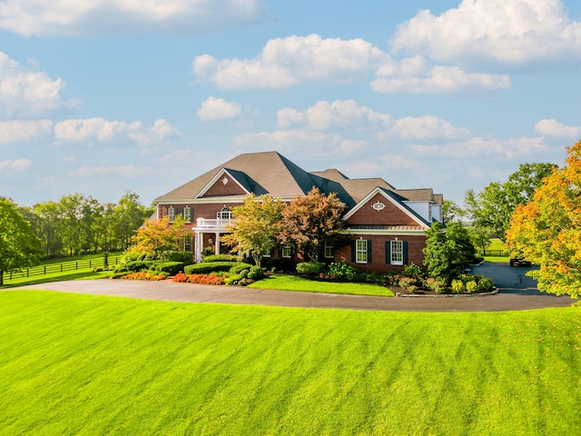 view of front of house featuring brick siding, a front yard, and fence