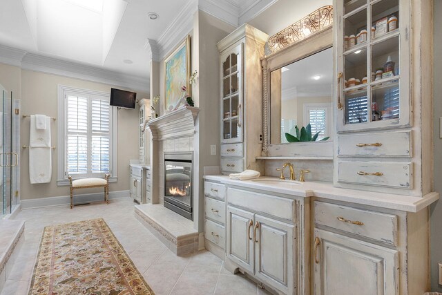 bathroom featuring tile patterned flooring, baseboards, ornamental molding, a tile fireplace, and vanity