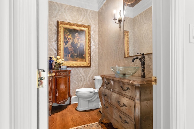 bathroom with wallpapered walls, toilet, ornamental molding, wood finished floors, and vanity