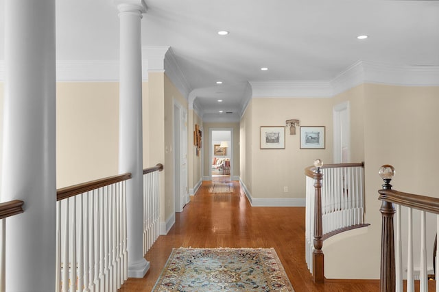 corridor featuring wood finished floors, baseboards, ornate columns, recessed lighting, and an upstairs landing