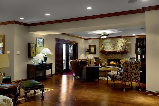 living room with a stone fireplace, ornamental molding, baseboards, and hardwood / wood-style flooring