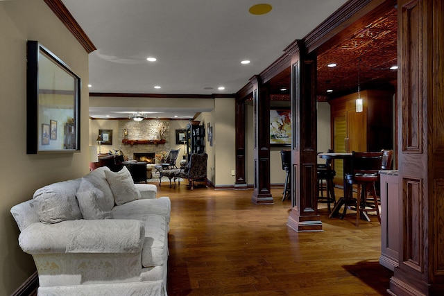 living area with ornamental molding, dark wood finished floors, recessed lighting, a fireplace, and ornate columns