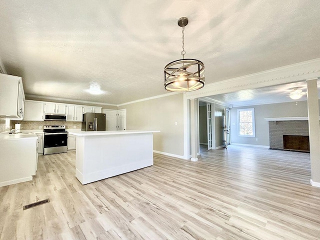 kitchen featuring white cabinetry, a brick fireplace, hanging light fixtures, ornamental molding, and appliances with stainless steel finishes