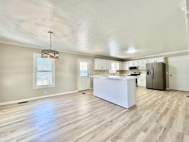 kitchen with white cabinetry, appliances with stainless steel finishes, light hardwood / wood-style flooring, and decorative light fixtures