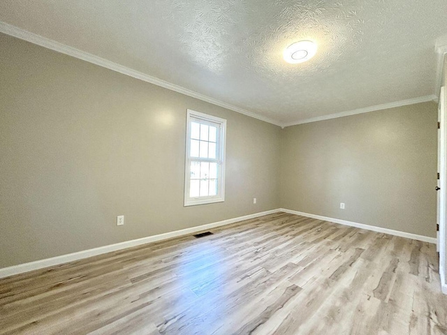 spare room featuring crown molding, light hardwood / wood-style floors, and a textured ceiling