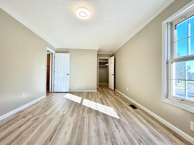 unfurnished bedroom featuring ornamental molding, a textured ceiling, light hardwood / wood-style floors, and a closet