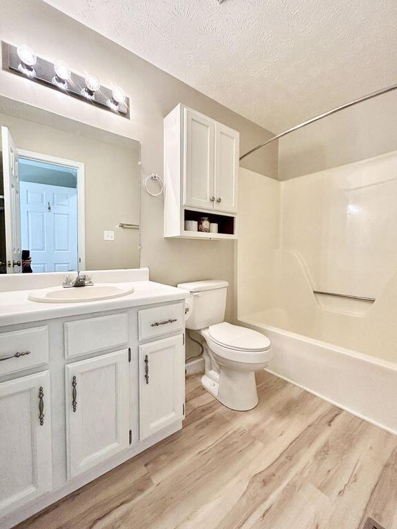 full bathroom with vanity, hardwood / wood-style floors, toilet, and a textured ceiling